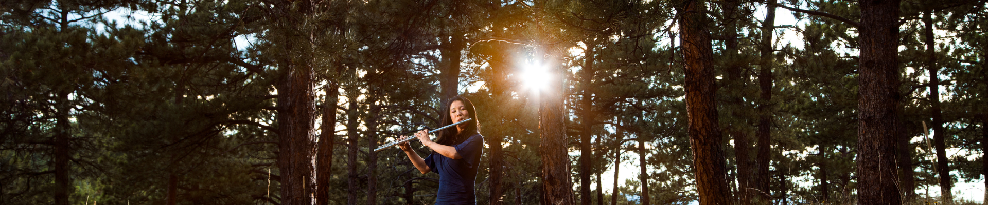 Catherie playing wind instrument in the woods