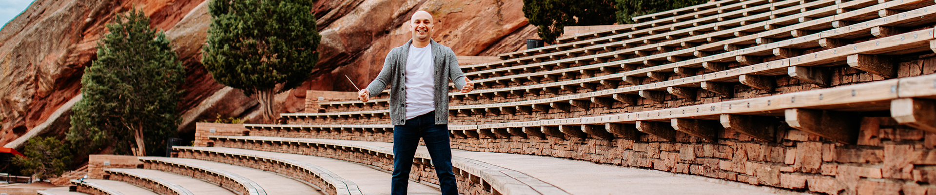Man with conductor stick stading in redrocks theater