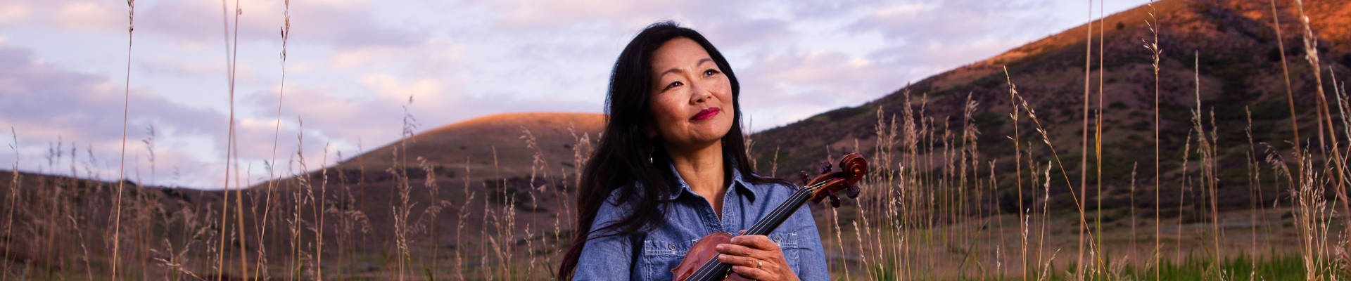 Yumi with violin standing in foothills